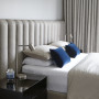 A neutral bedroom with soft drapes and blue pillows