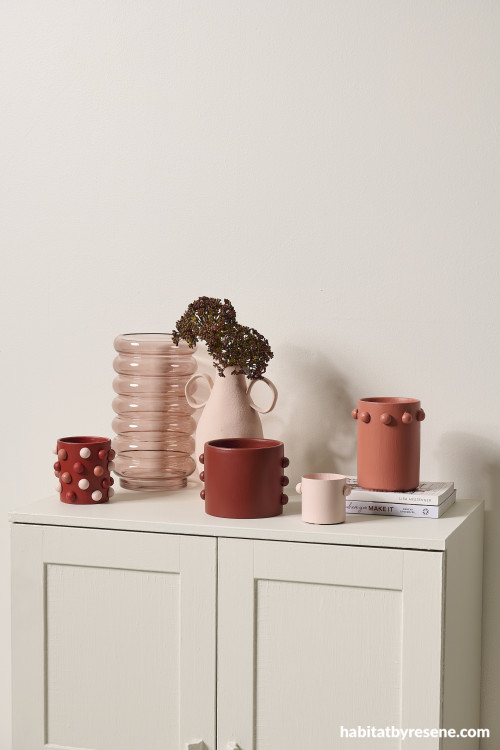 A cupboard with coloured vases on top