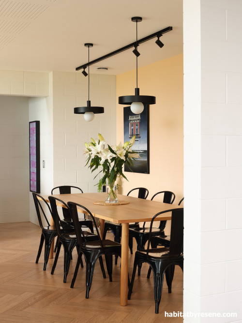 A dining room with a wooden table and black chairs and Resene Negroni on the walls