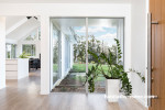 entranceway, wood front door, indoor plant, white living area, white house 